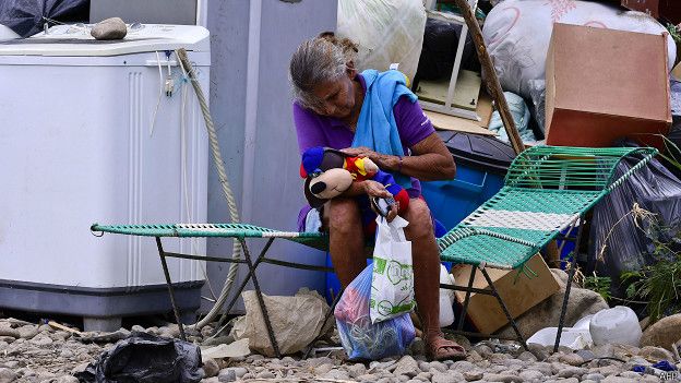 Mujer colombiana junto a sus pertenencias tras ser deportada de Venezuela