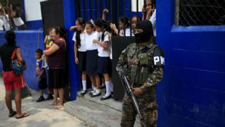 Un policía armado custodia la entrada de una escuela primaria en San Salvador