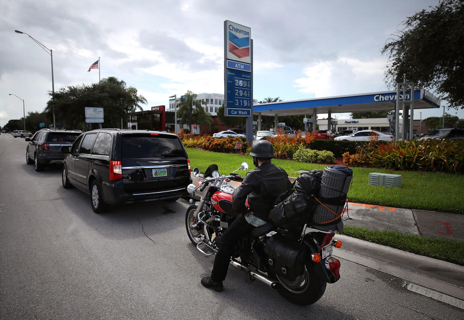 Largas filas en muchas estaciones de gasolina, como en esta de Doral, al...