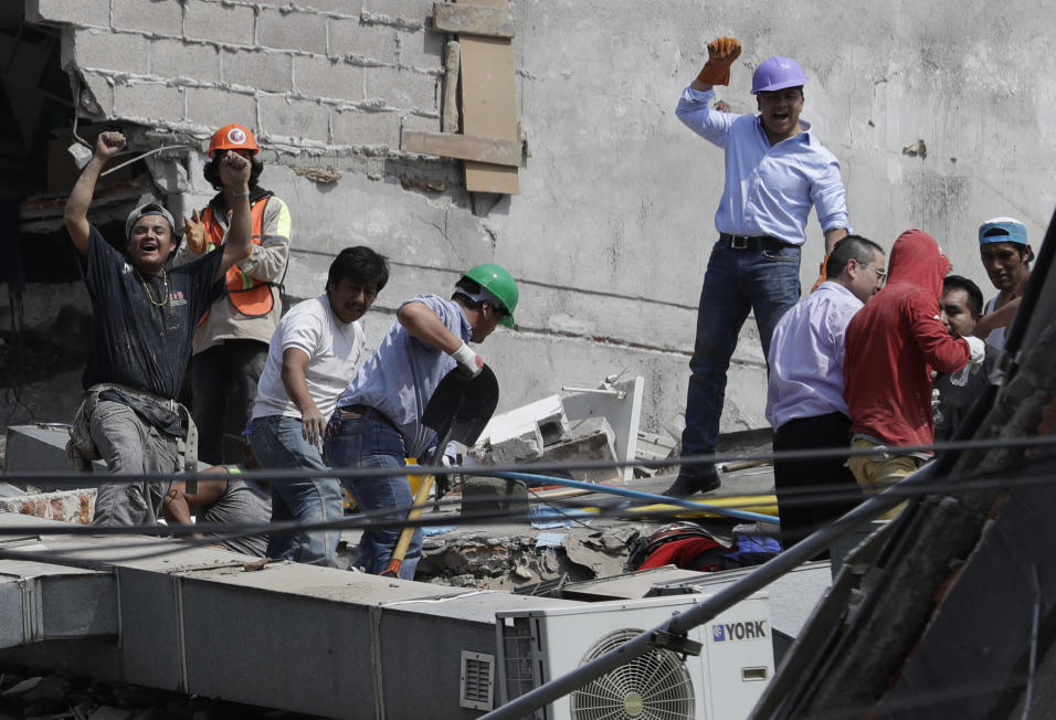 Voluntarios celebran brevemente el rescate de dos personas de un edifici...