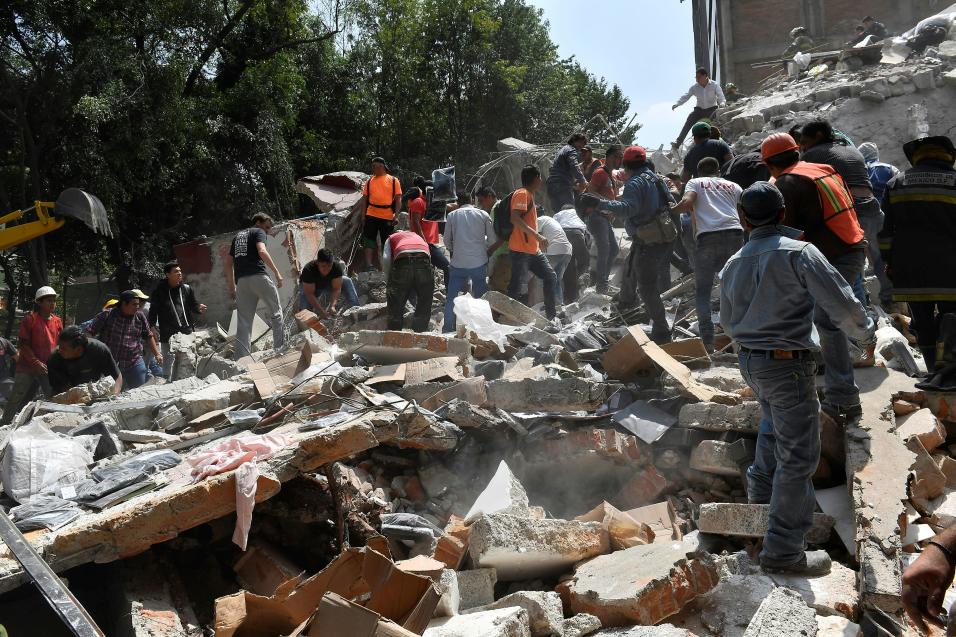 Voluntarios ayudan a remover escombros de un edificio que colaps&oacute;...