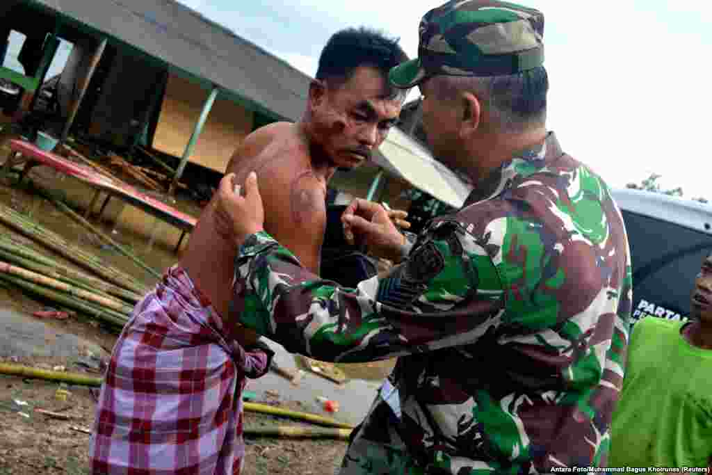 A soldier examines a local resident who was injured following a tsunami that hit at Tanjung Lesung district in Pandeglang, Banten province, Indonesia, Dec. 23, 2018.